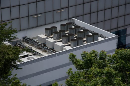 Commercial cooling HVAC air conditioner condenser on large commercial building rooftop for climate control and refrigeration temperature AC conditioning system