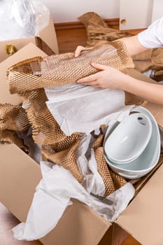 Detail of woman packaging fragile items using crumpled packing paper. Concept of moving in or out.