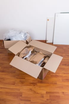 Moving boxes with packing material for fragile items on the floor. Concept of moving in or out.