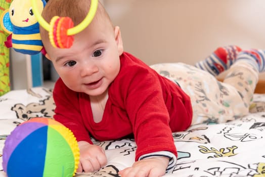 Adorable 6 months old little baby boy during tummy time surrounded by colourful toys