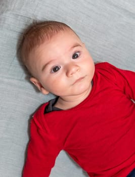 Adorable 6 months old little baby boy on his back looking up