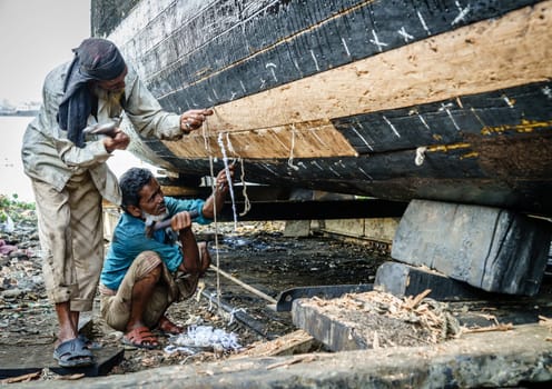 Chittagong, Bangladesh, December 22, 2017: Workers are building traditional fishing boats at a shipyard by the Karnaphuli River near Chittagong, Bangladesh