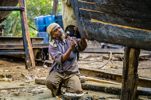 Chittagong, Bangladesh, December 22, 2017: Man is woring on a traditional fishing boats at a shipyard by the Karnaphuli River near Chittagong, Bangladesh