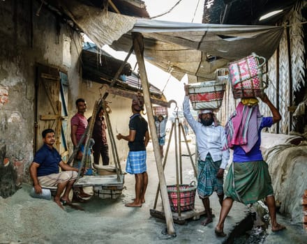 Chittagong, Bangladesh, December 22, 2017: Men weighing baskets with salt at a factory in Chittagong, Bangladesh