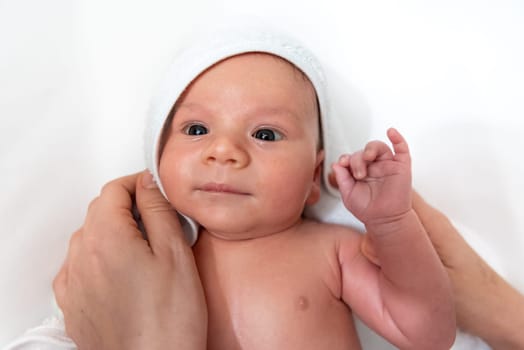Adorable 2 months old little baby boy on towel after bath in his mother's hands