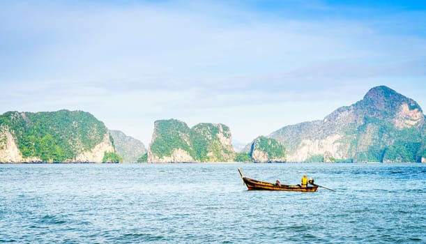 Traditional Thai motor boat in the Andaman Sea with Phuket coastline in the backdrop