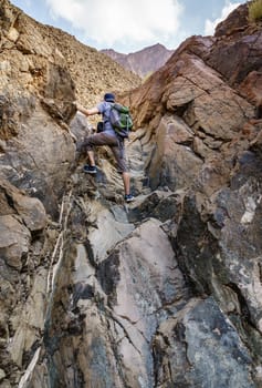 A man is hiking through a wadi in Hajar Mountains near Hatta, UAE