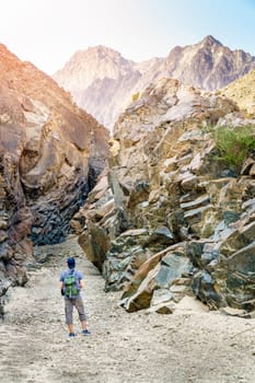 A man is hiking through a wadi in Hajar Mountains near Hatta, UAE
