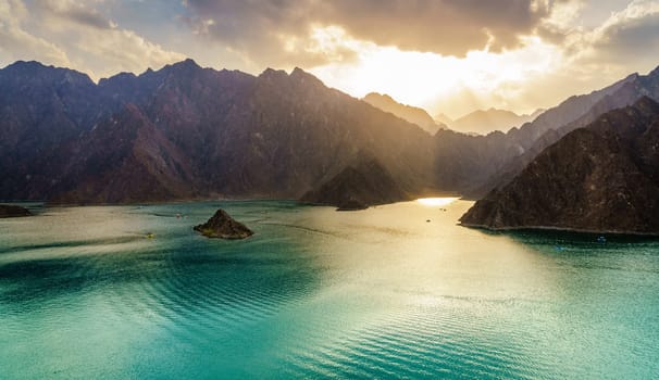 Scenic view of Hatta Lake and Hajar Mountains in the Emirate of Dubai, UAE at sunset