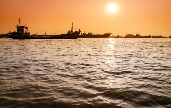 Commercial ships on anchorage in the Karnaphuli River in Bangladesh at sunset