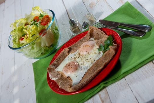 homemade Breton crepe with egg in a red plate