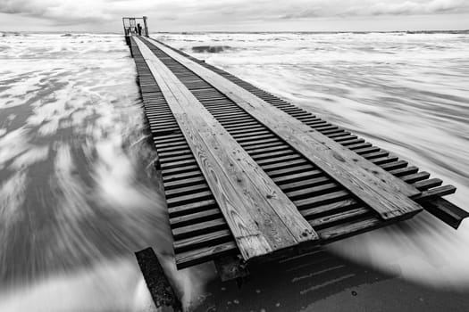 Long distance pier on the sea coast, black and white photo, long exposure