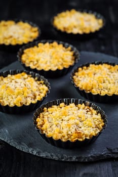 Small and delicious apple pies or apple crumble on black background. Apple tart.