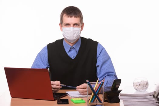 Portrait of a male office worker in a protective medical mask at the workplace