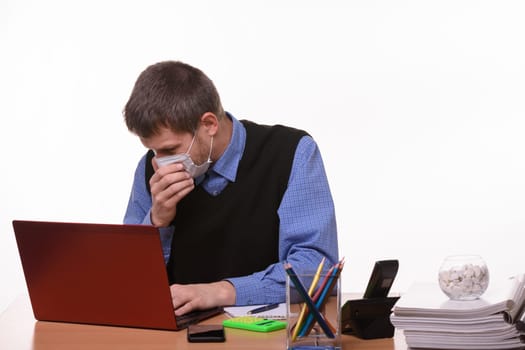 Office worker in medical mask sneezes at workplace