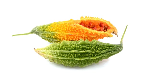 Two ripe bitter melons - green and overripe orange, split open with red seeds inside, isolated on a white background
