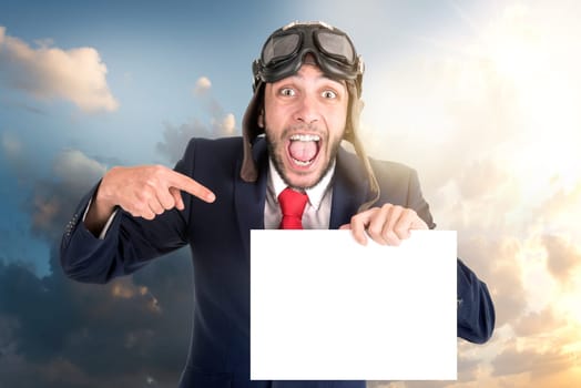Businessman with pilot goggles and white board posing against the sky