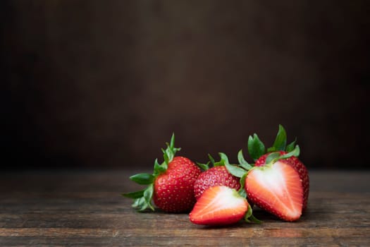 Fresh whole and sliced strawberry on dark wooden sufrace with copy space