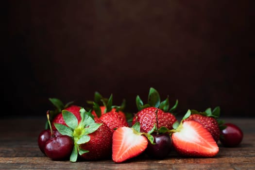Strawberries and cherries on wooden table with copy space