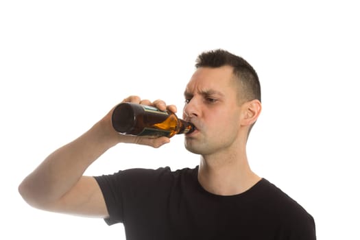 Casual young man drinking bottle of beer. Isolated on white.