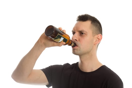 Casual young man drinking bottle of beer. Isolated on white.