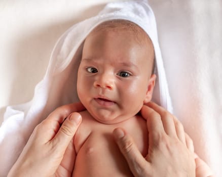 Adorable 2 months old little baby boy on towel after bath in his mother's hands