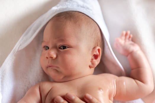 Adorable 2 months old little baby boy on towel after bath in his mother's hands