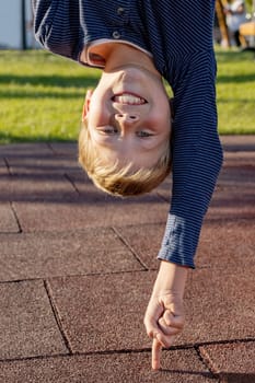 Boy upside down leaning on a finger outoors in the park. Concept for young people who do things easily