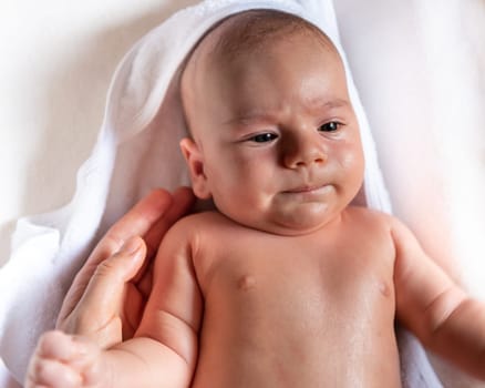 Adorable 2 months old little baby boy on towel after bath in his mother's hands