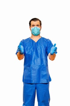 Male doctor in scrubs with protective face mask and gloves, inviting with open hands on plain white background. Coronavirus or covid 19 concept