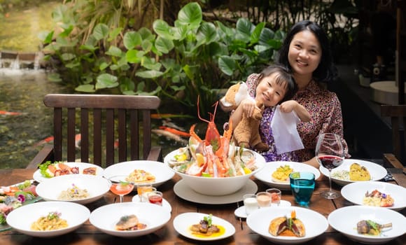 Portrait of mom and daughtersit at garden of restaurant of lobster shrimp steak beef lamb pasta spaghetti risotto rice sushi sashimi and wine using for buffet food drink background.