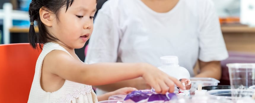 Panoramic asian girl kid playing colorful paper for art lesson at living room in home as home schooling while city lockdown because of covid-19 pandemic across the world with quaratine mom as teacher.