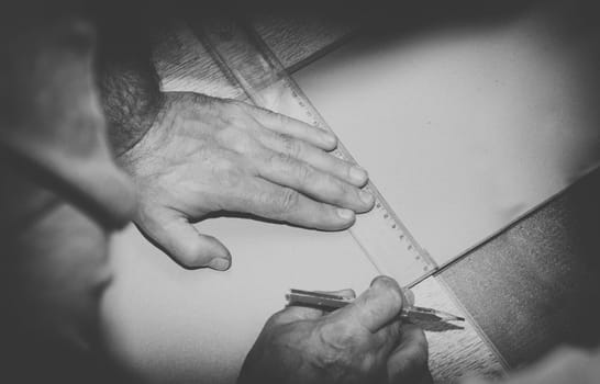 vintage photo of worker using a ruler to draw a line on a wood board