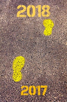 Yellow footsteps on sidewalk from Year 2017  to Year 2018 messages.New Years Conceptual image