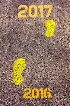Yellow footsteps on sidewalk from Year 2016  to Year 2017 messages.New Years Conceptual image