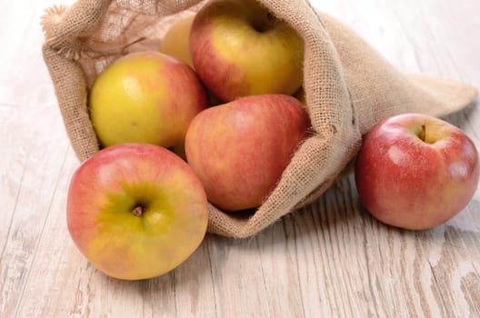 Fresh apples in a canvas net on a rustic wooden table