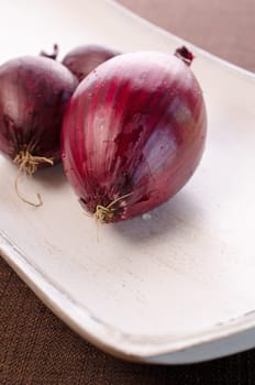Red onions on a white wooden bowl
