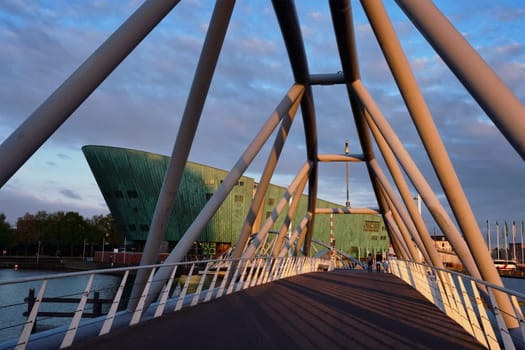 AMSTERDAM, NETHERLANDS - MAY 9, 2017: NEMO Science museum and Mr. J.J. van der Veldebrug bridge. It is the largest science center in Netherlands with over 500000 visitors per year