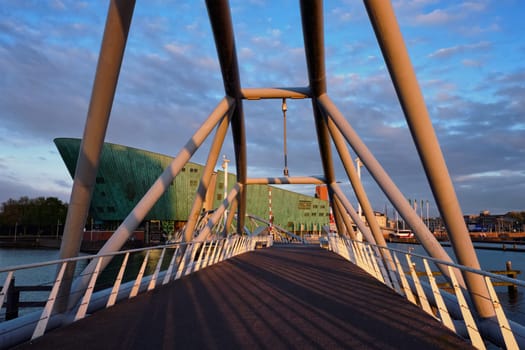 AMSTERDAM, NETHERLANDS - MAY 9, 2017: NEMO Science museum and Mr. J.J. van der Veldebrug bridge. It is the largest science center in Netherlands with over 500000 visitors per year