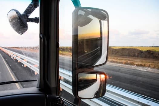 In the cockpit of a truck at dawn. Large rear-view mirrors