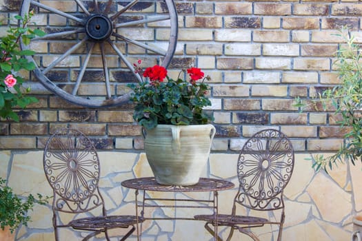 beautiful place in the garden in the mediterranean style, pot with pelargonium on the table