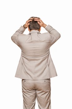 Back view of middle age businessman in beige suite pulling his hair out as his business falling during recession, isolated on white background