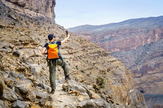 A hiker is taking selfie in Jebel Shams, Oman