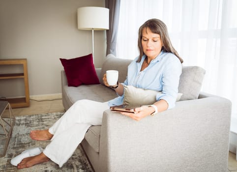 Mature woman looking at a tablet screen in her urban apartment