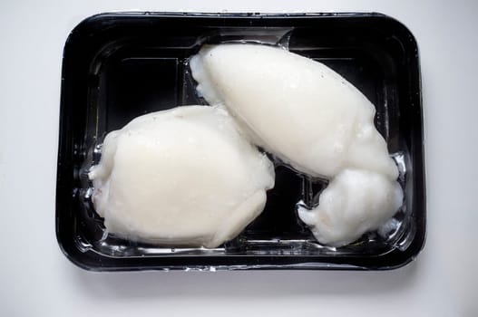 Tray of whole frozen cuttlefish. Overhead shot
