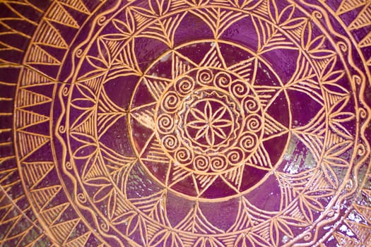 Traditional pattern of tile mandala bowl pottery. Golden and purple colors, close up