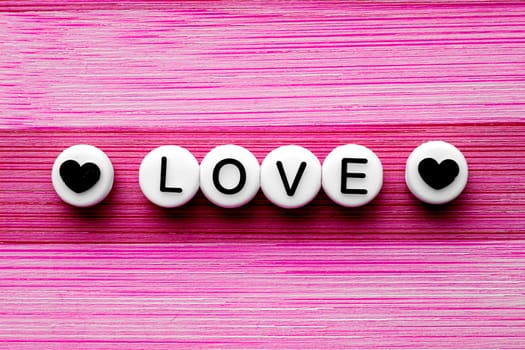 Love text with hearts on the side on a pink wooden table