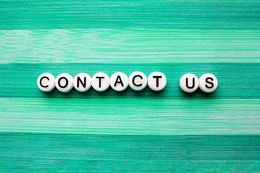 Contact us text on a green wooden table