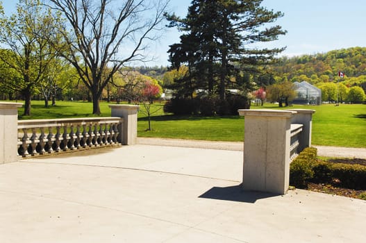 A entrance to a park in Hamilton in the spring with a new greenhouse.in the back.
