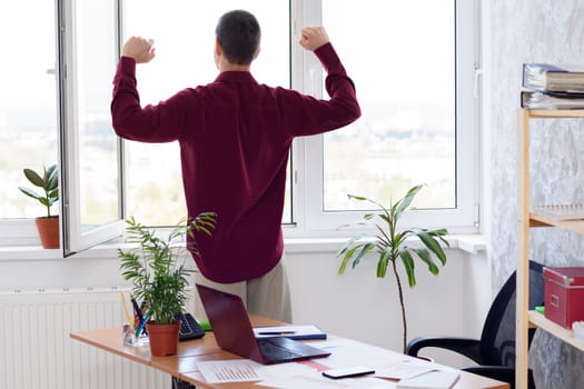 Office worker does gymnastics standing by the window